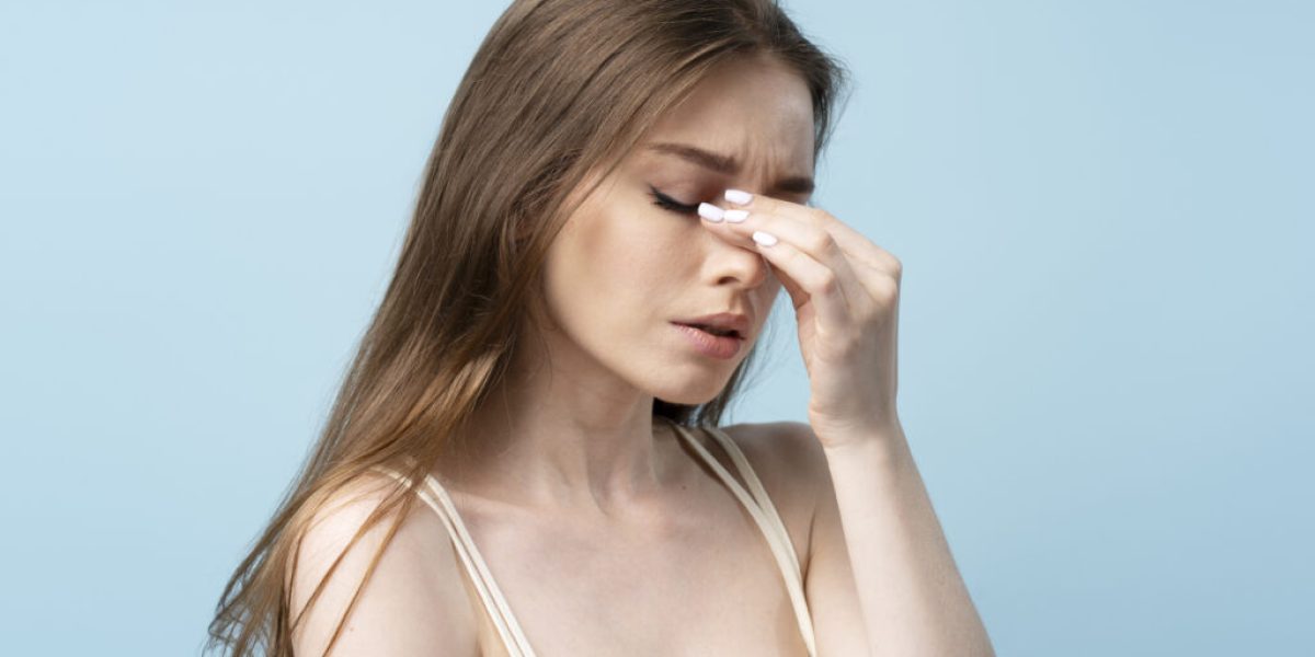 Portrait of tired woman with long hair with headache, migraine solated on blue background. Sad girl with closed eyes has bad news, feeling bad. Depression concept